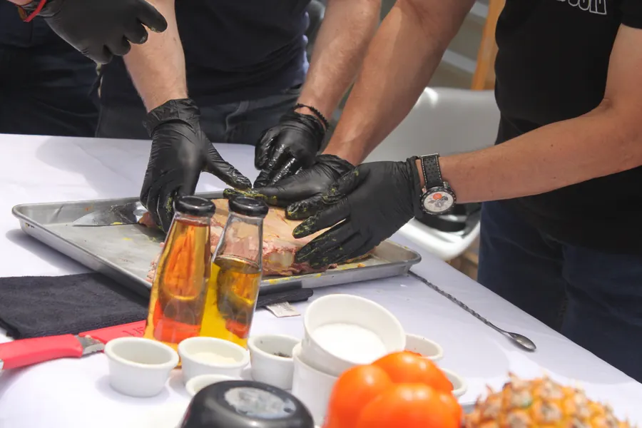 Grupo de alumnos preparando un corte de carne en equipo sobre charola